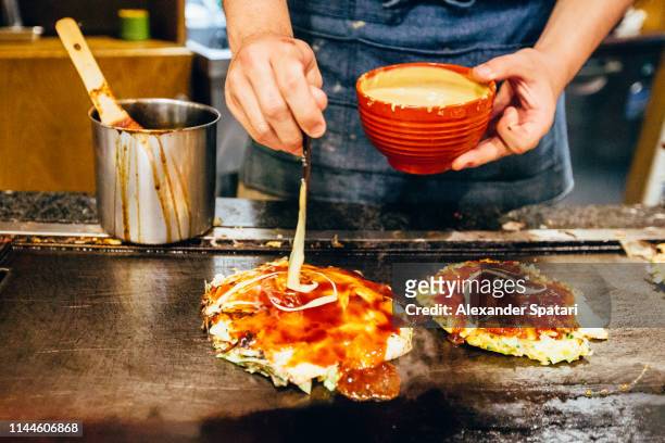 chef cooking okonomiyaki at japanese restaurant - okonomiyaki stock pictures, royalty-free photos & images