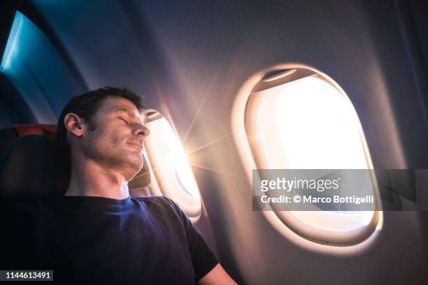 man sleeping on airplane during sunrise - comfortable flight stock pictures, royalty-free photos & images