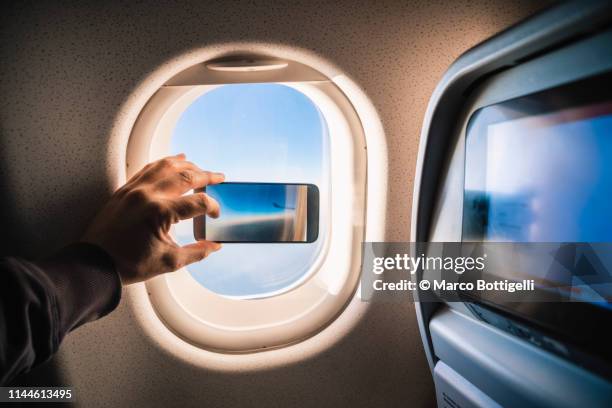 personal perspective of man taking picture through airplane window - different perspective stock-fotos und bilder