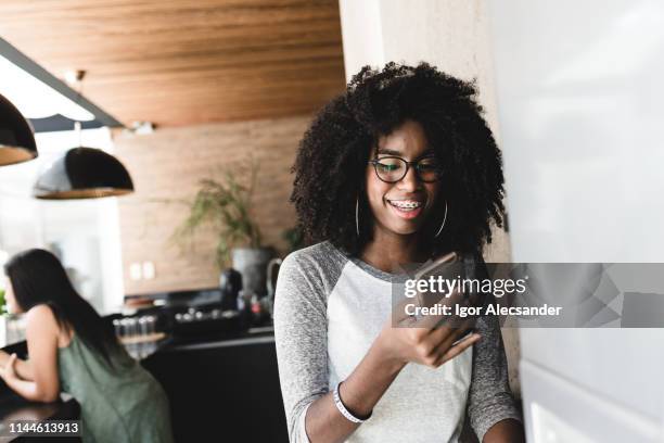 tiener met behulp van cellulaire voor entertainment - oorringen stockfoto's en -beelden