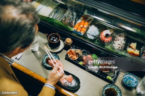 japanese male eating sushi - sushi restaurant stock pictures, royalty-free photos & images