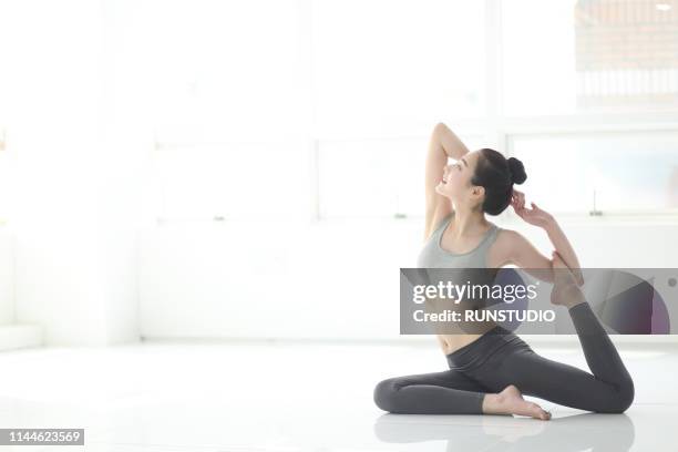 woman practicing yoga in living room - grand prix of japan practice stockfoto's en -beelden