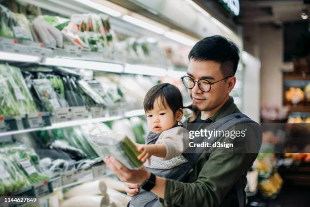 young asian father with cute little daughter grocery shopping for fresh organic vegetables in supermarket - supermercado fotografías e imágenes de stock