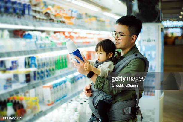 young asian father with cute little daughter grocery shopping for dairy products in supermarket - 2 coconut drinks ストックフォトと画像
