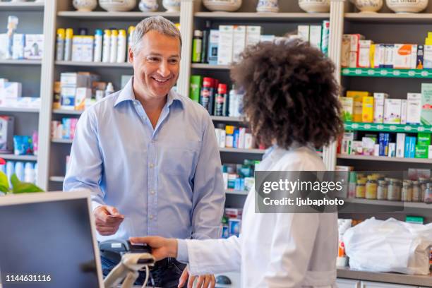 mature man paying with credit card - paying doctor stock pictures, royalty-free photos & images