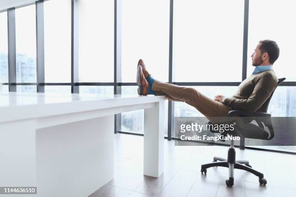 businessman sitting with legs up on desk viewing city - feet up stock pictures, royalty-free photos & images