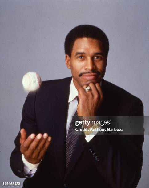 Portrait of American baseball player Dave Winfield, of the New York Yankees, dressed in a suit and tie as he throws a baseball into the air, 1980s.