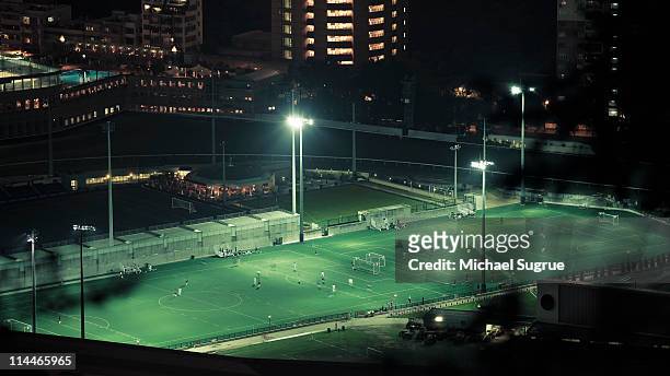 people play at a soccer field at night, hong kong. - stadium hong kong stockfoto's en -beelden