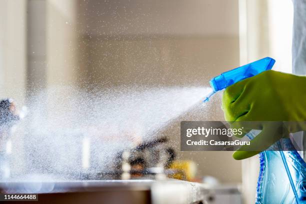 spraying cleaning product on the kitchen counter - líquido de limpeza imagens e fotografias de stock