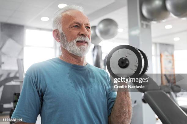 senior man på fitness center arbetar med vikt på en biceps - tyngdlyftning bildbanksfoton och bilder