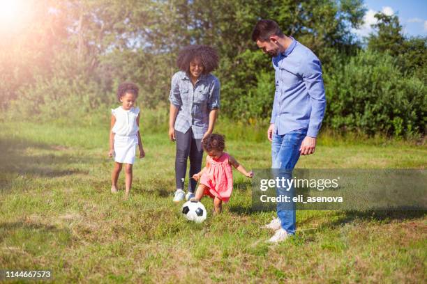 family outdoors in summer playing soccer game in park - mother of all balls stock pictures, royalty-free photos & images