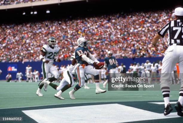 Mark Clayton of the Miami Dolphins scores a touchdown against the New York Jets during an NFL football game November 27, 1988 at Giants Stadium in...