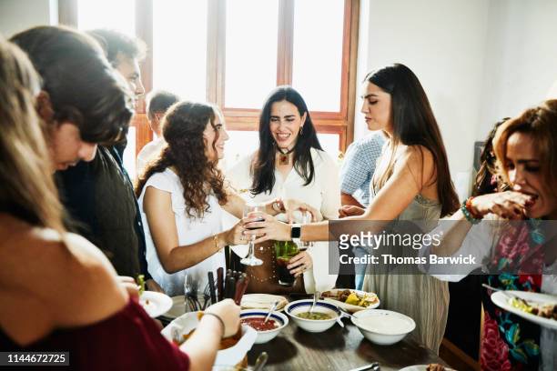 Smiling mother hanging out with daughters in kitchen during family dinner party
