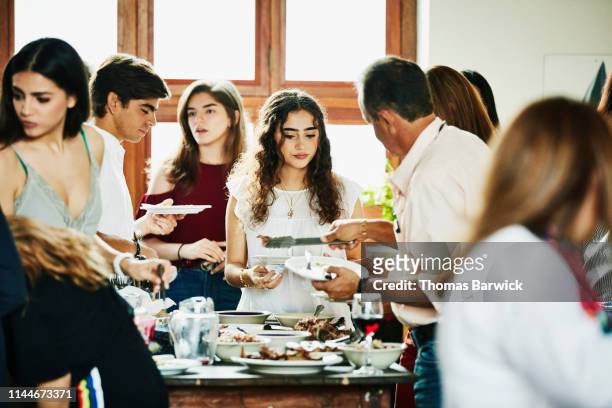 Young woman being served food during multigenerational family dinner party