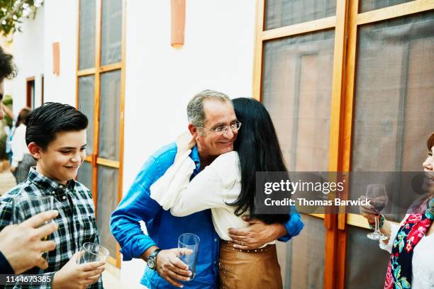 Husband and wife embracing during family dinner party in backyard