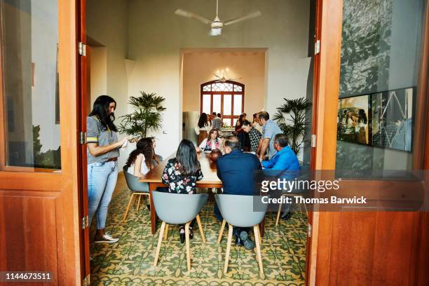 multigenerational family hanging out in dining room during dinner party - annual safeway feast of sharing stockfoto's en -beelden