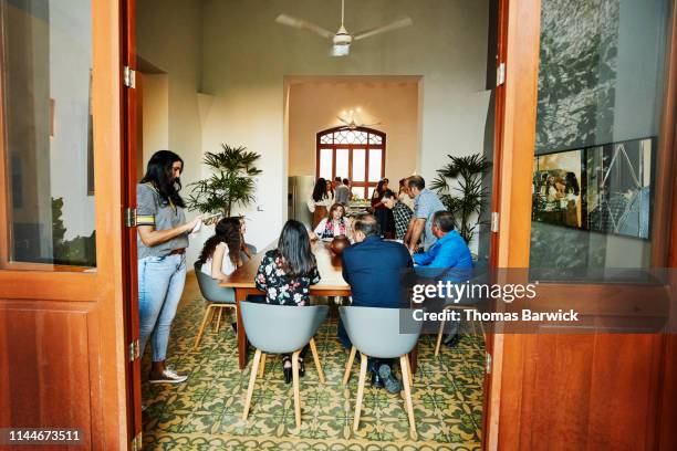 multigenerational family hanging out in dining room during dinner party - share house stock pictures, royalty-free photos & images