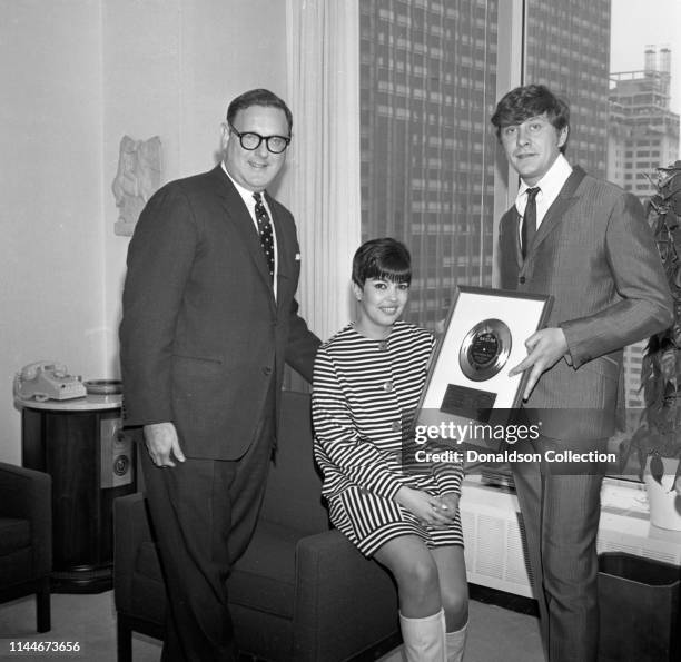 Producer Mickie Most receives a gold record award with his wife Christina Hayes from Mort Nasatir at MGM Records on April 17, 1967 in New York.