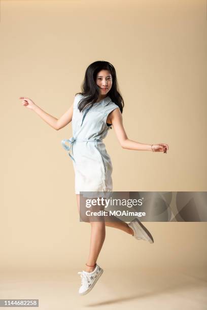 portrait of a young asian lady in a studio shot - denim skirt ストックフォトと画像