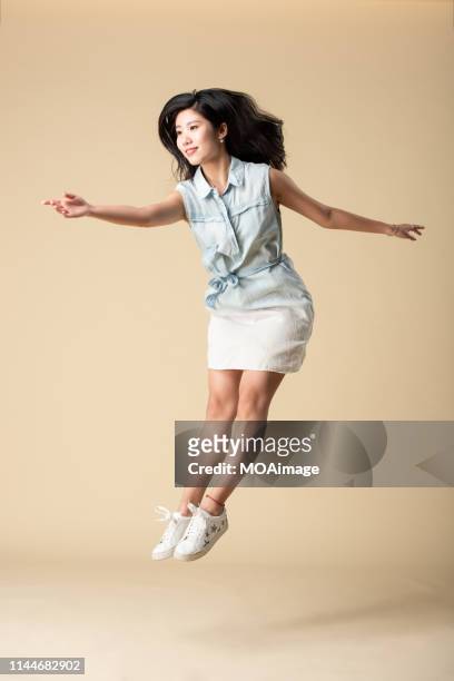portrait of a young asian lady in a studio shot - jumping casual clothing studio shot stock-fotos und bilder