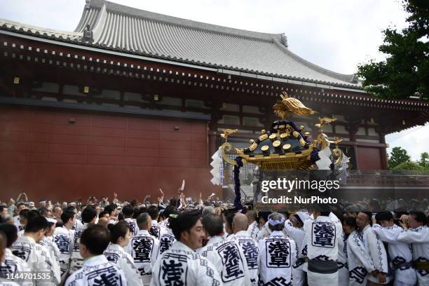 Participants clad in traditional happi coats carry a portable shrine in Sensoji Temple during Tokyo's one of the largest three day festival called...