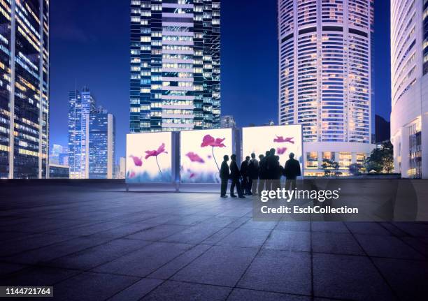 illuminated hong kong skyline with people looking at flower images - exhibition people stock pictures, royalty-free photos & images