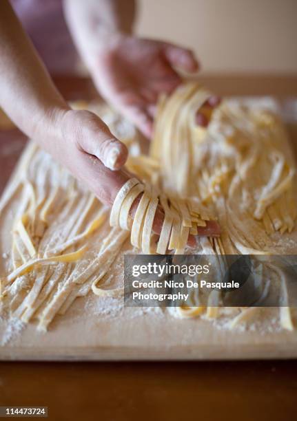 hands of woman sorting some tagliatelle - tagliatelle fotografías e imágenes de stock