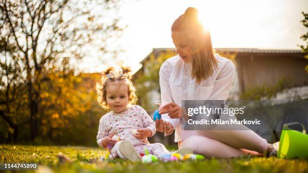 jugando en el césped junto a la casa durante la pascua - egg hunting fotografías e imágenes de stock