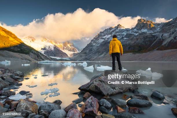 man looking at view at sunrise in los glaciers national park, argentina - geel jak stockfoto's en -beelden