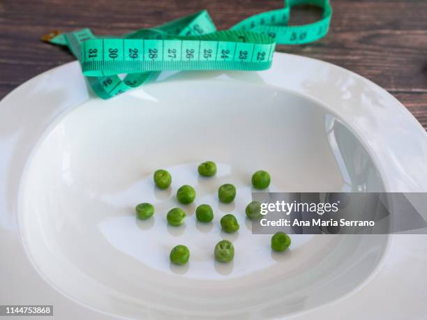 a few peas on a plate and a tape measure. diet concept - anorexia nervosa stock pictures, royalty-free photos & images