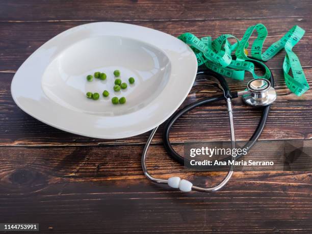 a few peas, a stethoscope and a tape measure. diet and health concept - bulimie stock-fotos und bilder