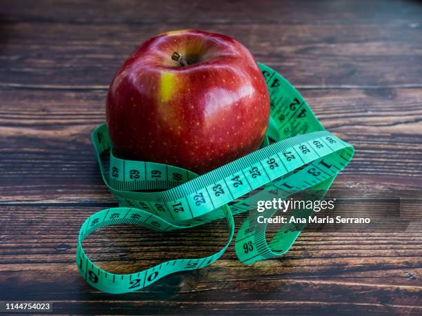 an apple and a tape measure. diet concept - bulimie stock-fotos und bilder