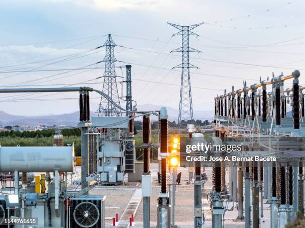 electrical transformer of high tension in a distribution electric power station of electricity power. - transformador fotografías e imágenes de stock