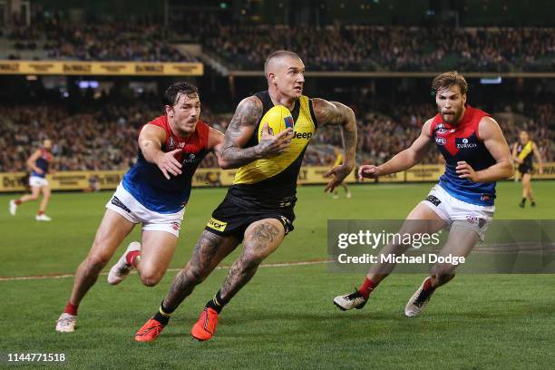 Dustin Martin of the Tigers runs with the ball from Michael Hibberd and Jack Viney of the Demons during the round 6 AFL match between Richmond and...