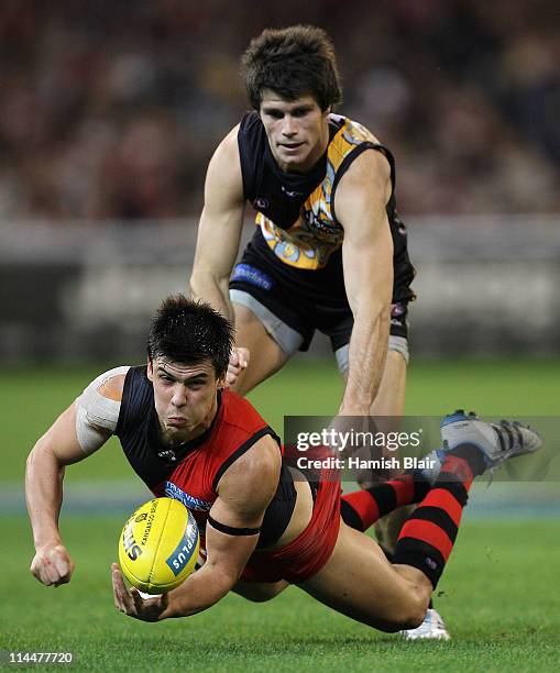 Angus Monfries of the Bombers handpasses as he is tackled by Trent Cotchin of the Tigers during the round nine AFL match between the Richmond Tigers...