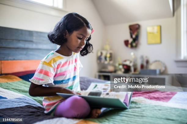 girl reading book on her bed - kids read fotografías e imágenes de stock