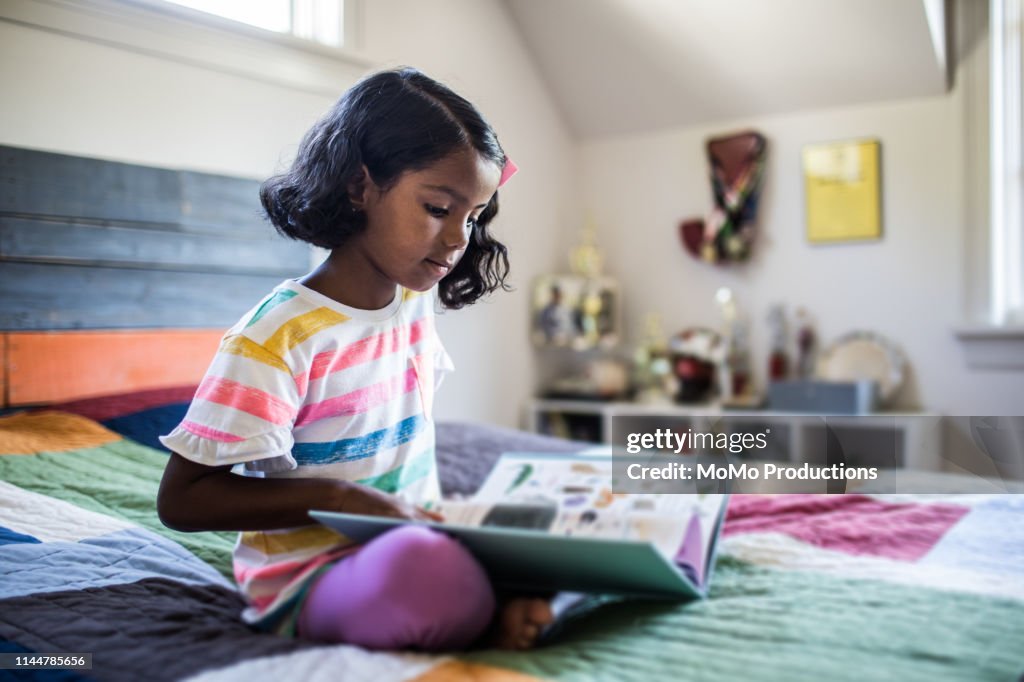 Girl reading book on her bed