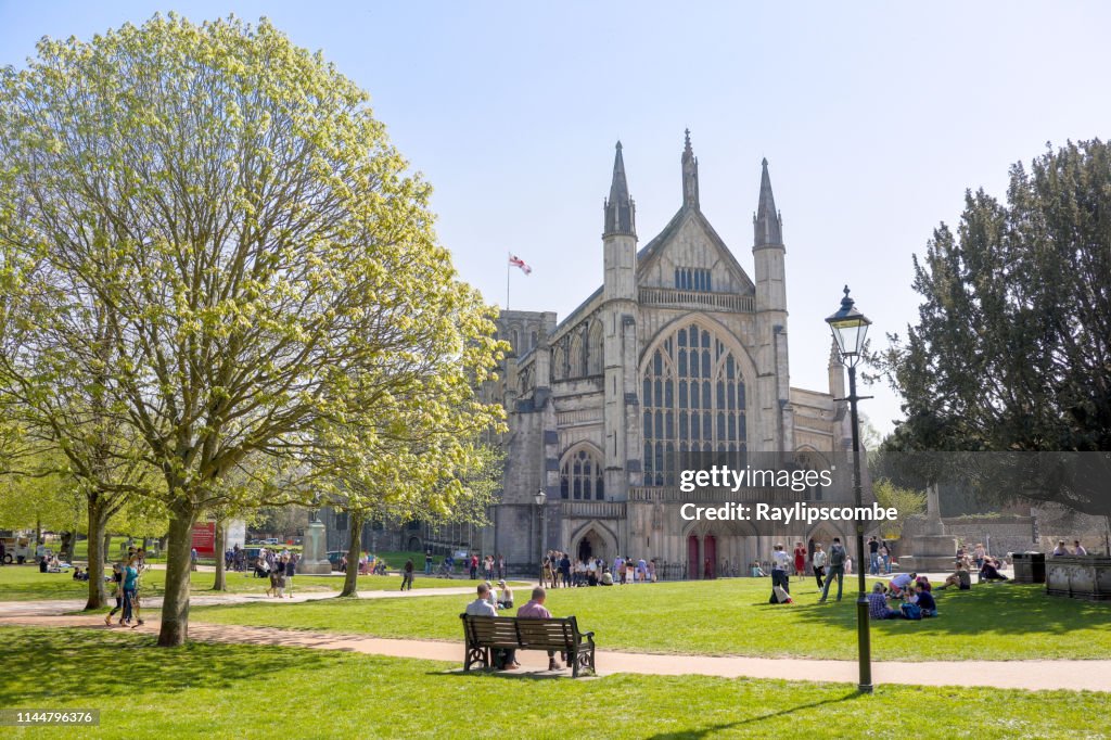 Los turistas y visitantes sentados alrededor de la famosa catedral de Winchester en el cálido Domingo de Pascua Sunshine a finales de abril