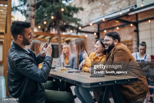 friends sitting outdoors in cafe - sidewalk cafe stock pictures, royalty-free photos & images