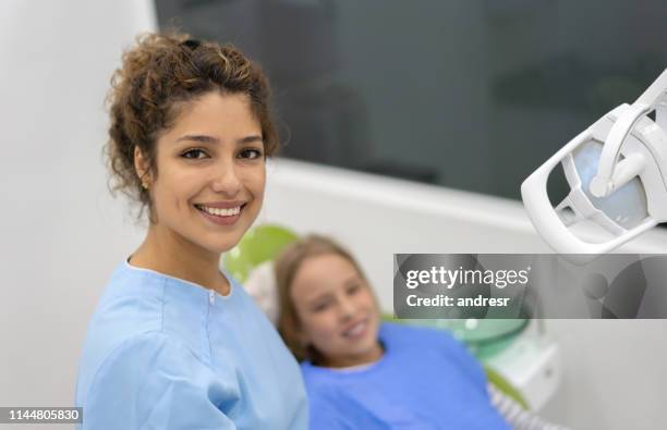 happy tandarts het controleren van een girlâs tanden - tandartsassistent stockfoto's en -beelden