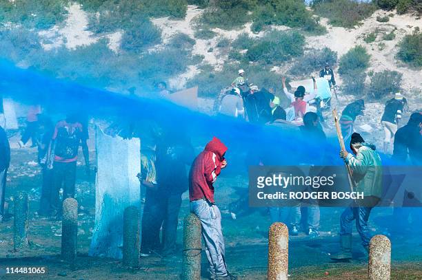 Members of the South African Police Services spray a mixture of blue dye, water, and tear gas at squatters on May 17, 2011 in Tafelsig, Mitchells...