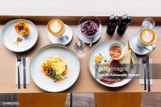 high angle view of brunch with eggs benedict and english breakfast in a cafe - cereal bar fotografías e imágenes de stock