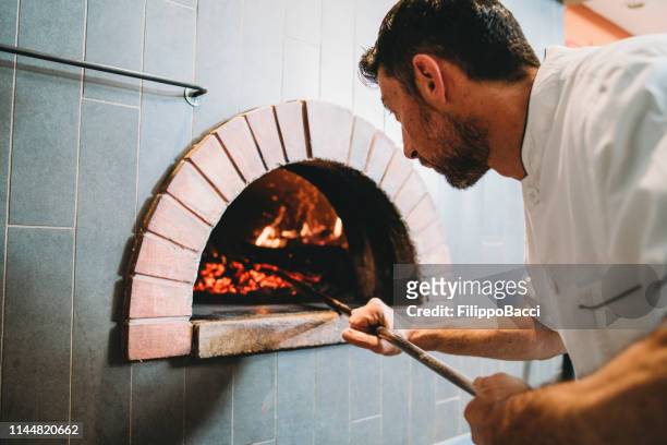 彼のピッツェリアのオーブンをチェックピザシェフ - pizzeria ストックフォトと画像