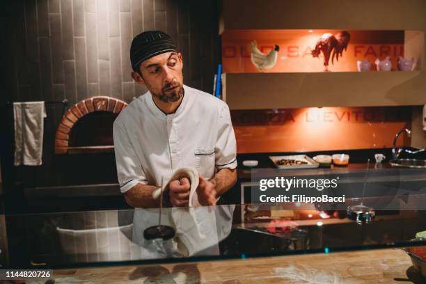 pizza chef preparing a pizza at the restaurant - pizza chef stock pictures, royalty-free photos & images