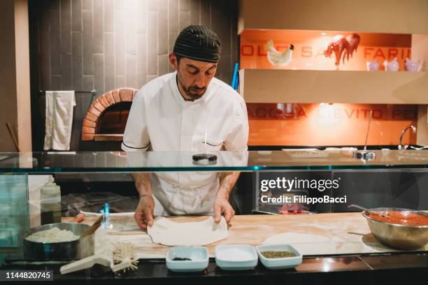 pizza chef preparing a pizza at the restaurant - pizza chef stock pictures, royalty-free photos & images