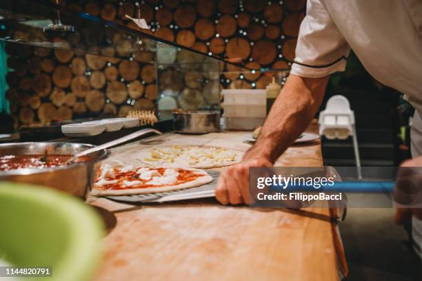 pizza chef preparing a pizza at the restaurant - pizza chef stock pictures, royalty-free photos & images