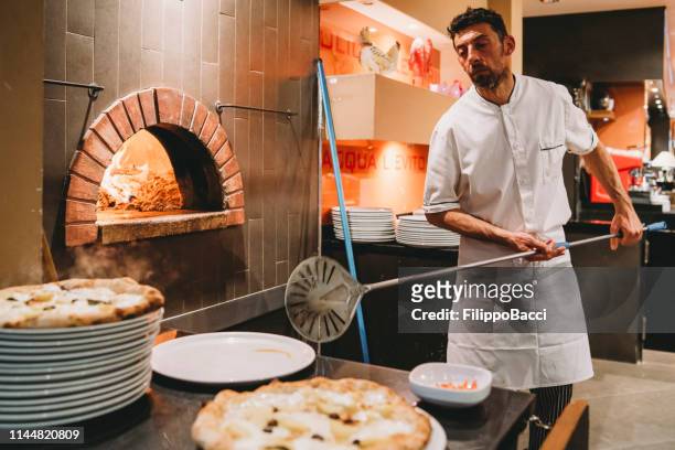 pizza chef preparing pizza at the restaurant - pizza chef stock pictures, royalty-free photos & images