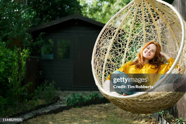 woman relaxing on garden swing seat - columpio para la terraza fotografías e imágenes de stock