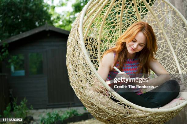 woman writing in journal on swing seat outside - memorial garden stock pictures, royalty-free photos & images