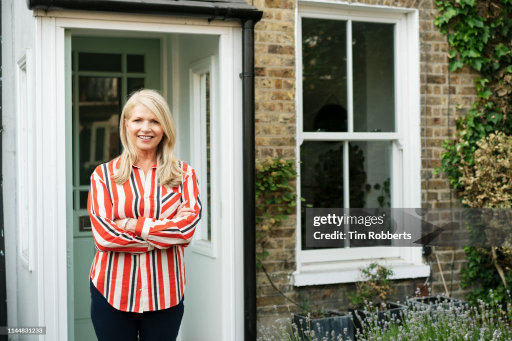 Woman with arms crossed outside house